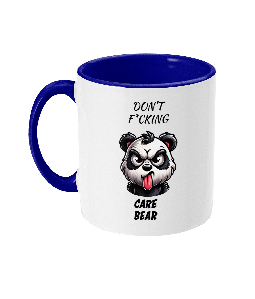  A white ceramic coffee mug with a blue handle and interior. The design features a fierce cartoon panda with an angry expression, sticking out its tongue. Above and below the panda, the text reads, “Don’t F*cking Care Bear,” in bold, playful fonts, emphasizing the cheeky humor of the design.