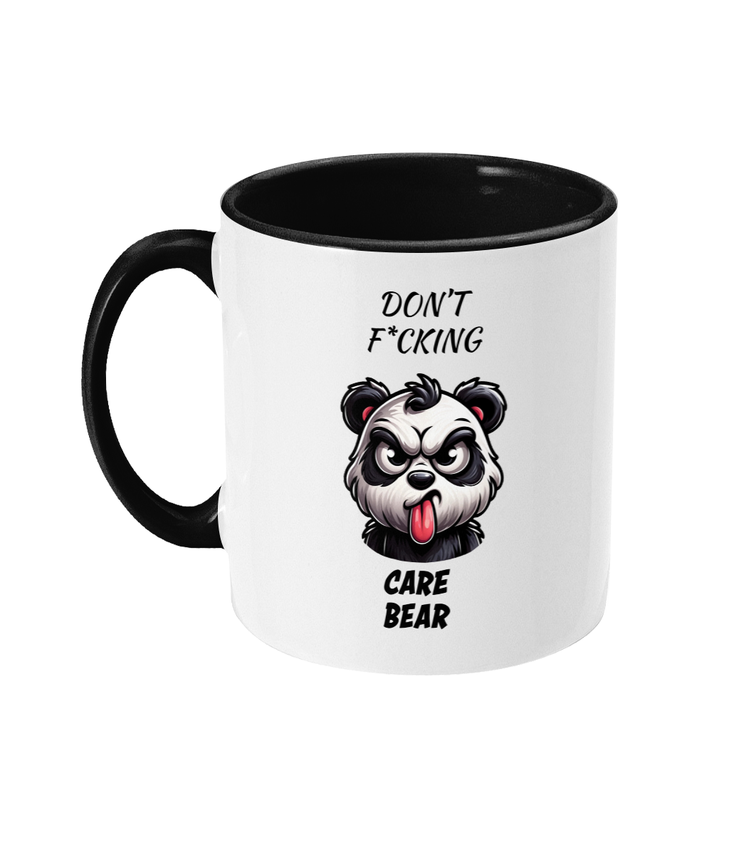  A white ceramic coffee mug with a black handle and interior. The design features a fierce cartoon panda with an angry expression, sticking out its tongue. Above and below the panda, the text reads, “Don’t F*cking Care Bear,” in bold, playful fonts, emphasizing the cheeky humor of the design.