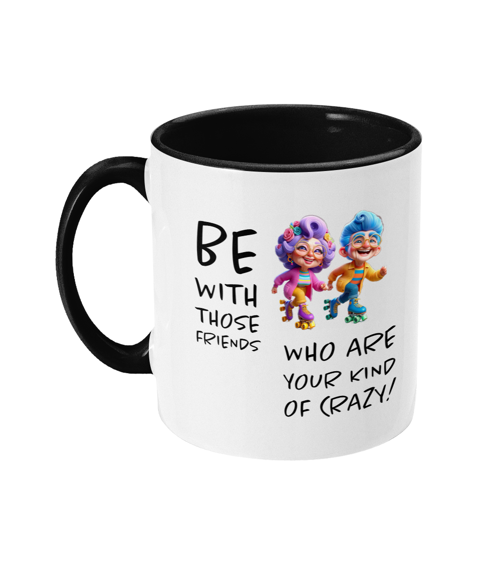  A white ceramic coffee mug with a black interior and handle, featuring the playful phrase “Be with those friends who are your kind of crazy!” The design includes colorful cartoon illustrations of two eccentric characters on roller skates, exuding a fun and energetic vibe. The text is styled in a casual, handwritten font.