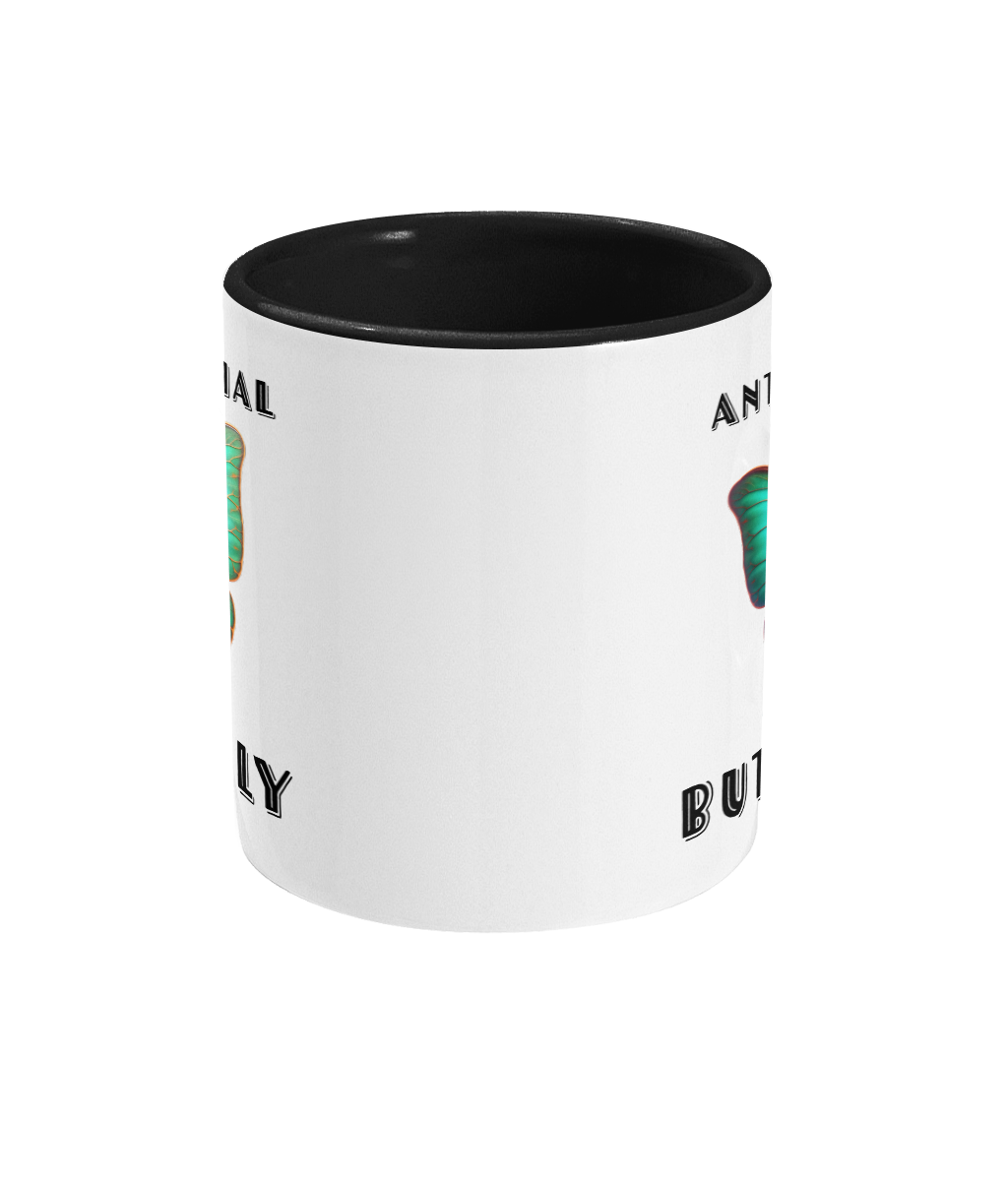  A white ceramic coffee mug with a black interior and handle, featuring the phrase “Anti-Social Butterfly” in bold, playful font. The design includes a cute, colorful cartoon butterfly holding a leaf as if hiding, adding a humorous and quirky touch.