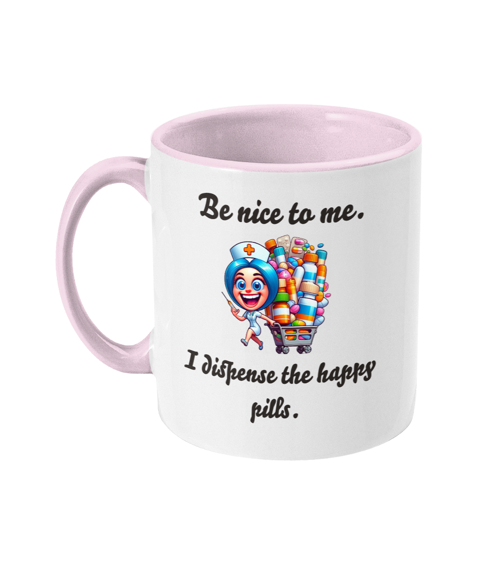 A white ceramic coffee mug with a pink interior and handle, featuring the humorous text, “Be nice to me. I dispense the happy pills.” The design includes a colorful cartoon illustration of a cheerful nurse holding a syringe and standing next to a cart overflowing with colorful pill bottles, adding a playful and lighthearted touch.